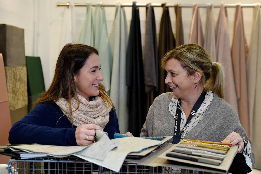 a buyer speaking with a supplier and sampling their fabrics at cruise ship interiors expo europe