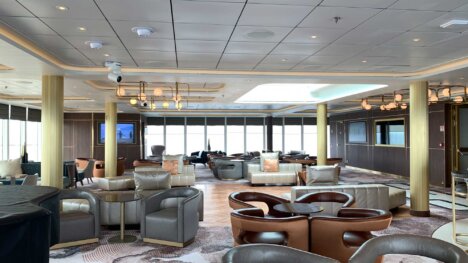 palm court aboard crystal endeavour, a bar with a wall of windows, and grey leather seats around round wooden tables